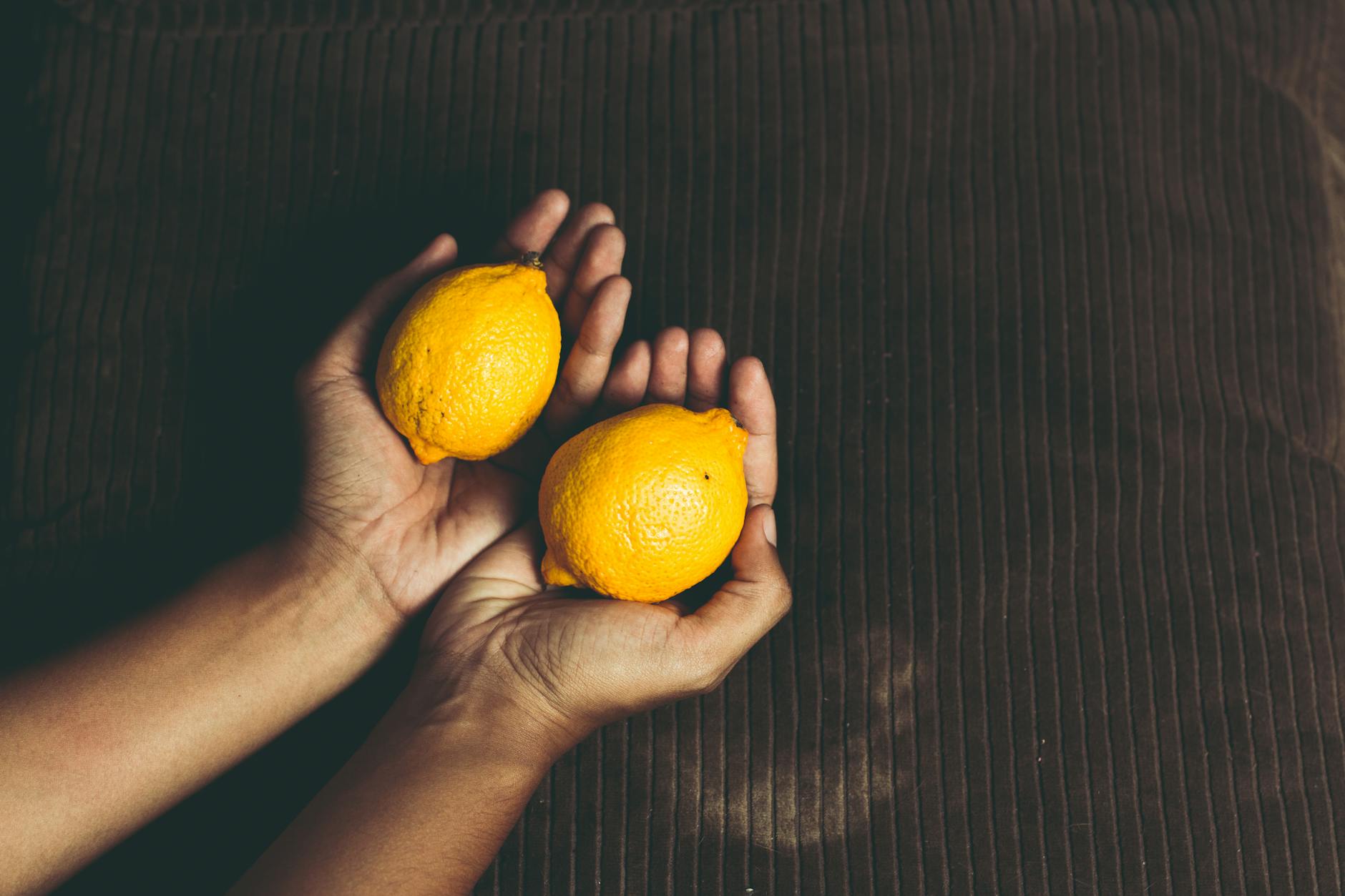 Cupped hands holding two fresh lemons symbolizing renewed sensation