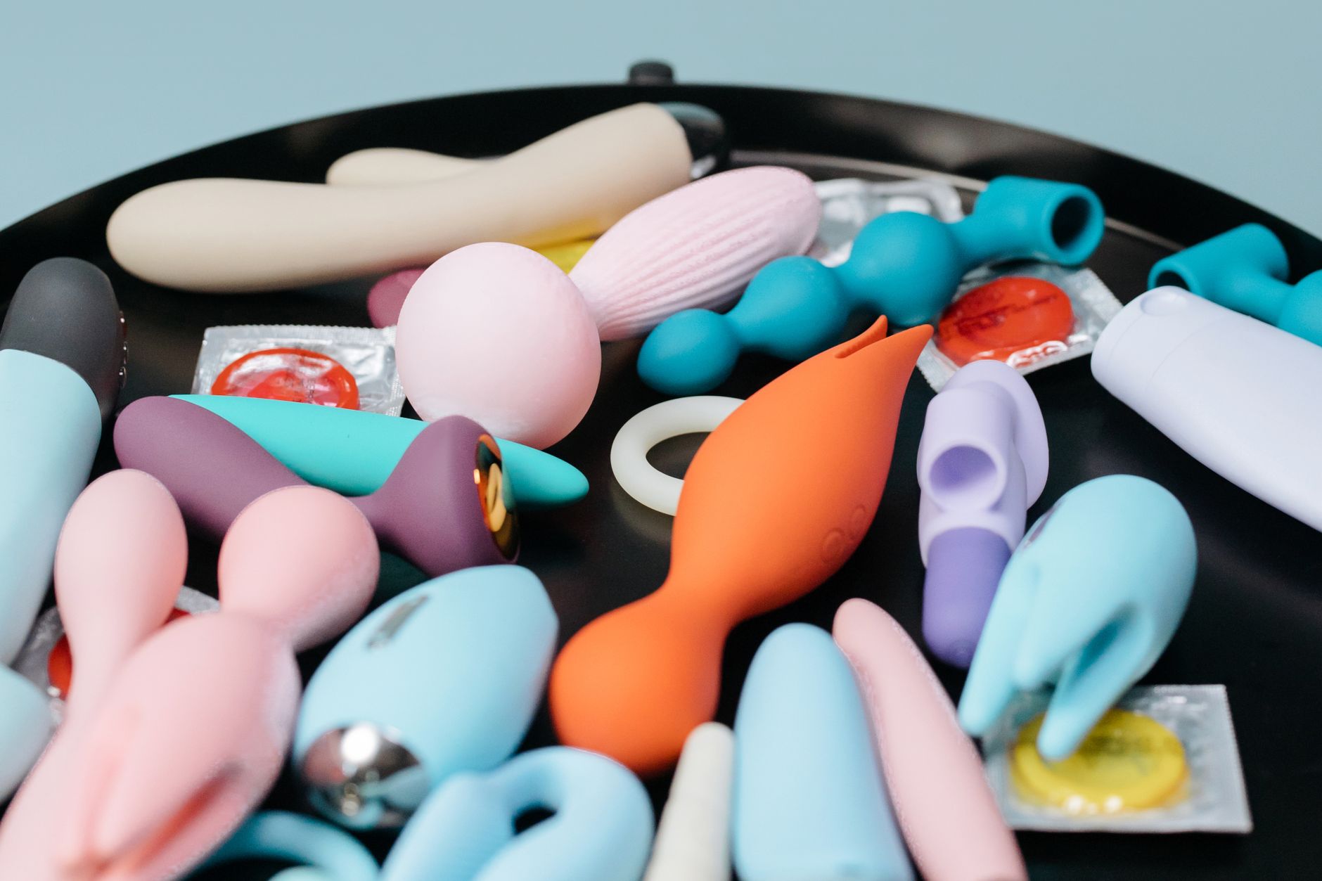 A vibrant collection of various colorful sex toys on a black tray