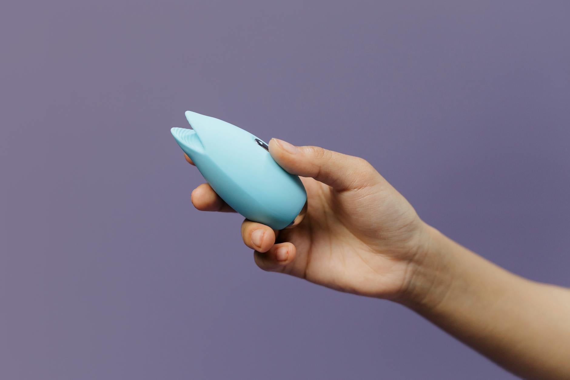 A blue silicone vibrator held against a purple background, highlighting modern toy design and material quality