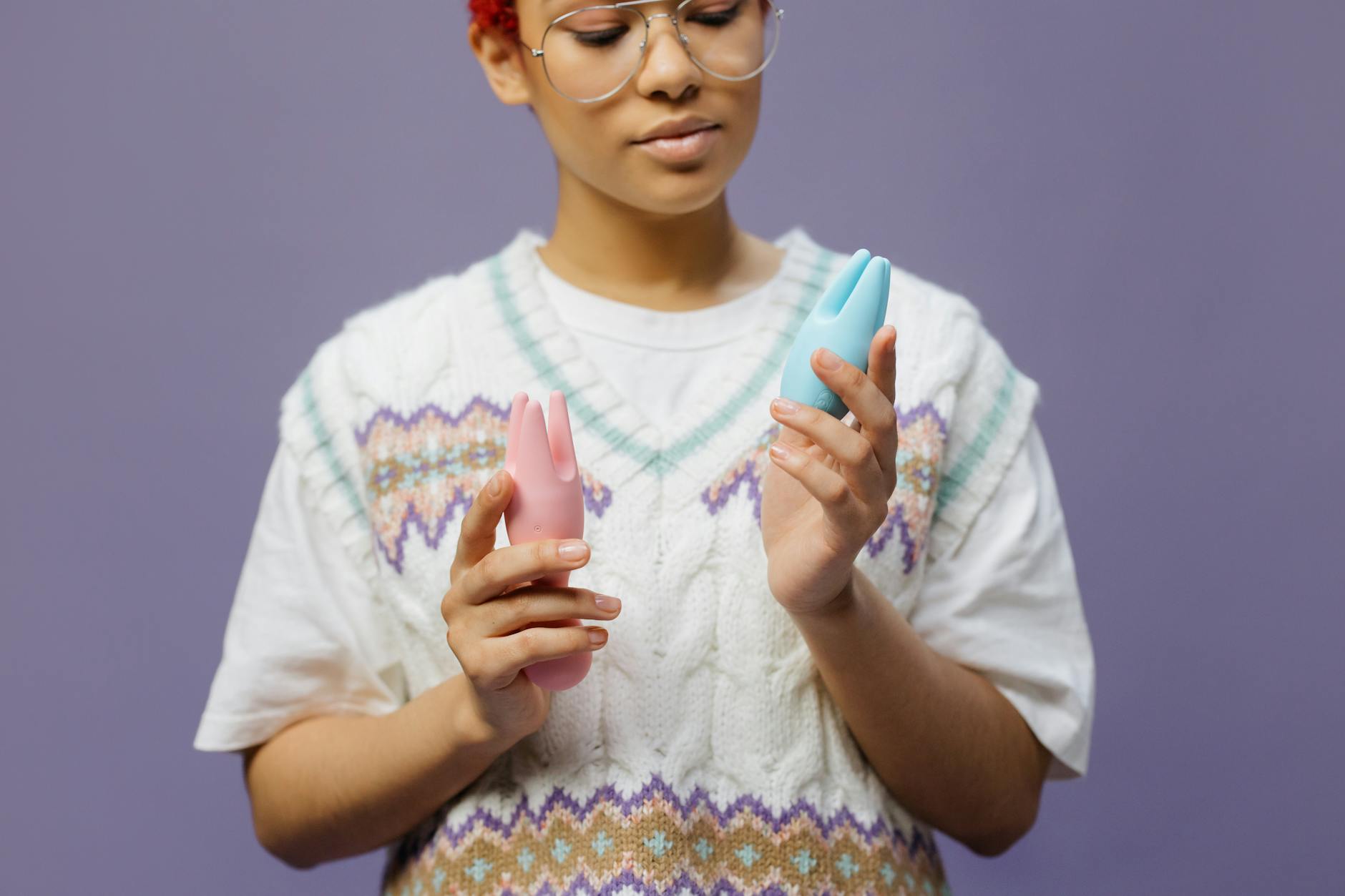 Woman holding multiple clitoral vibrators and considering which sensation type matches her needs