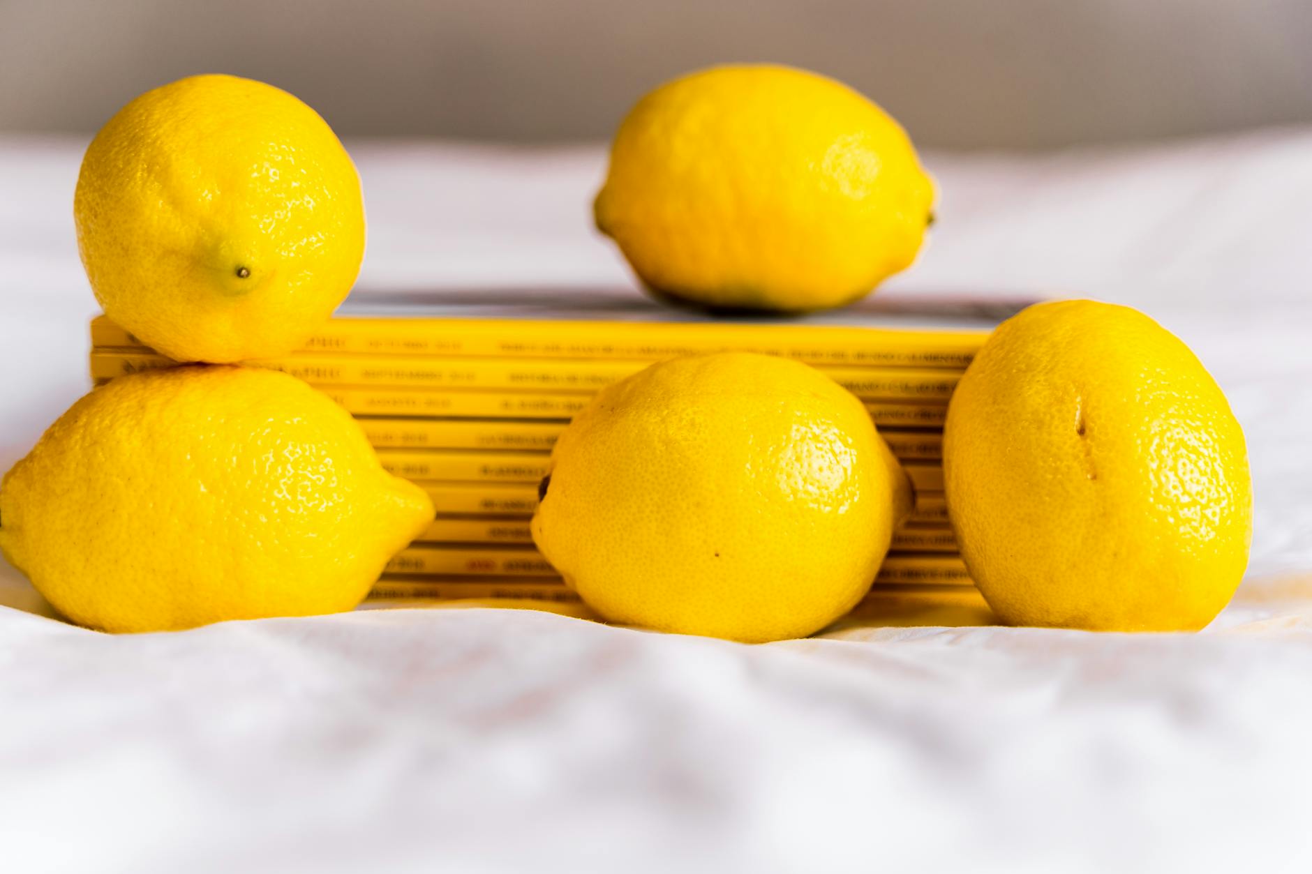 Fresh yellow lemons with stacked books on white tablecloth, symbolizing wisdom and pleasure discovery